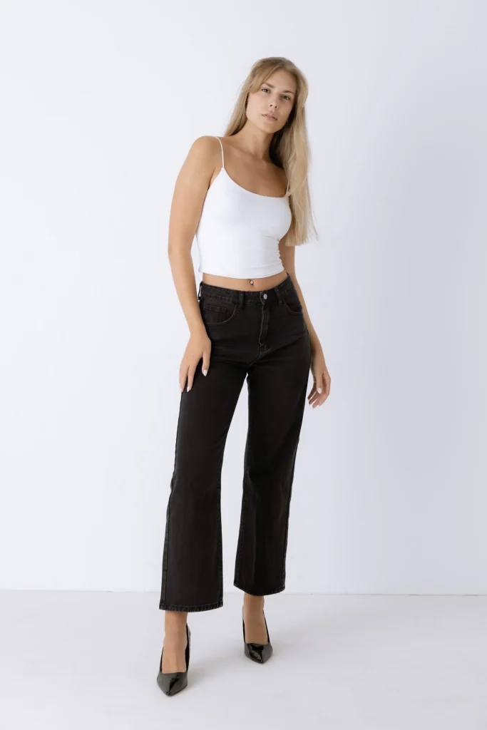 Model trägt weißes Top und schwarze Cropped-Jeans