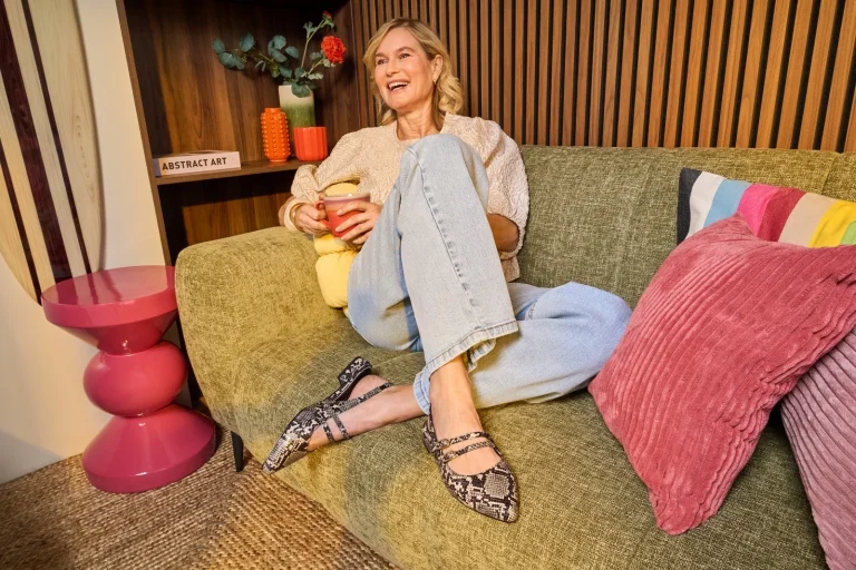 Lachende Frau mit Tasse auf grünem Sofa