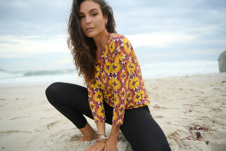 Frau sitzt am Strand vor dem Meer