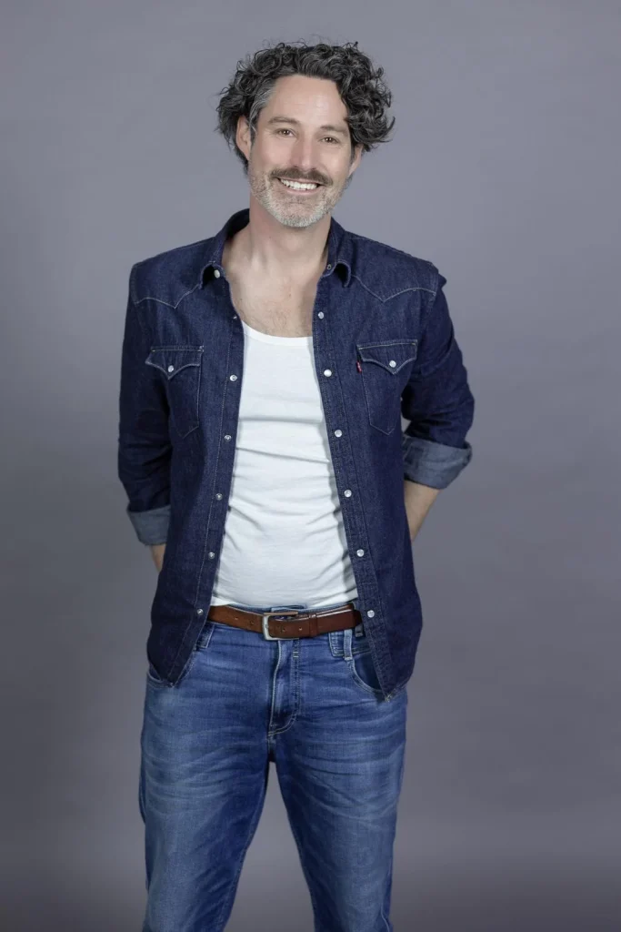 Lächelnder Mann im Jeanshemd vor grauem Hintergrund