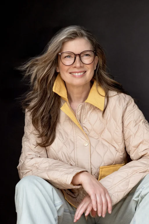 Lächelnde Frau mit Brille und beiger Steppjacke
