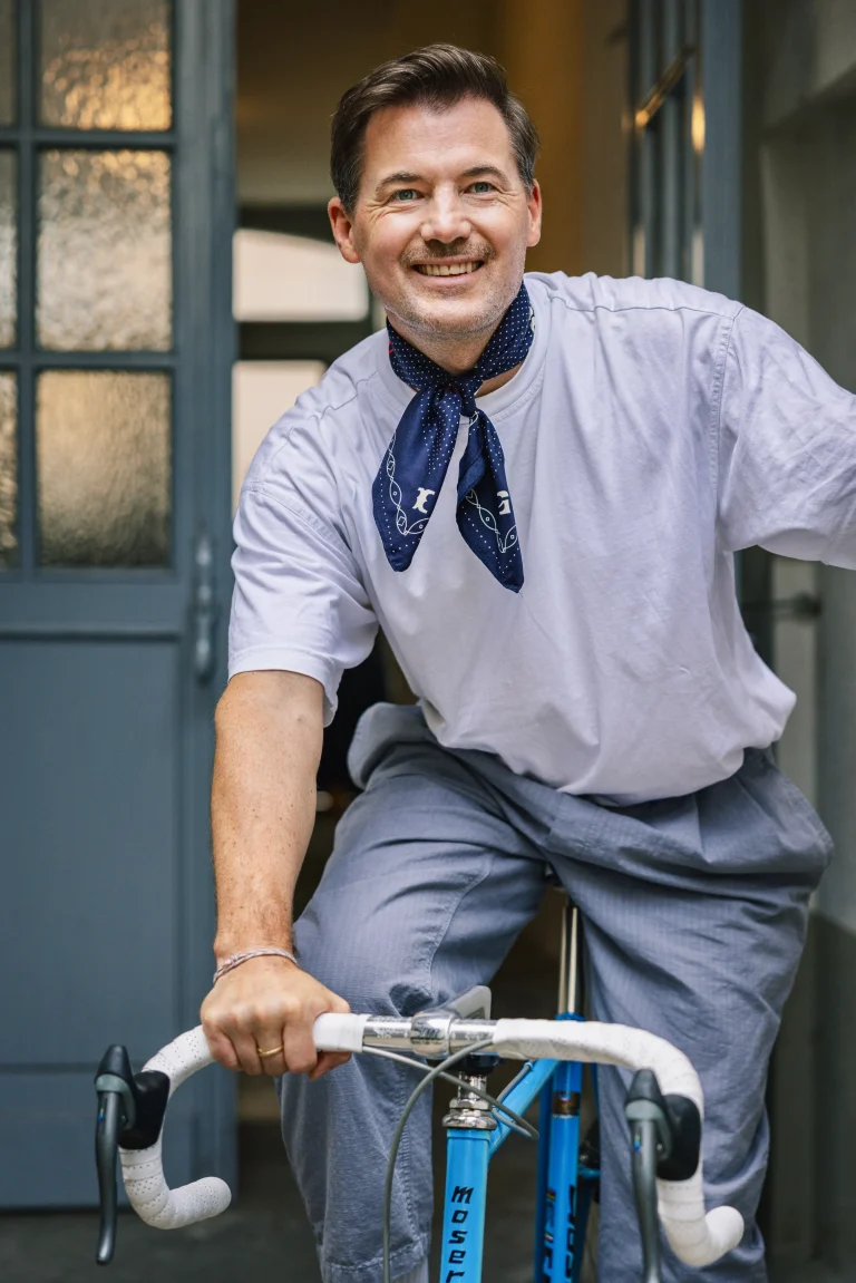 Lächelnder Mann auf blauem Fahrrad vor Tür