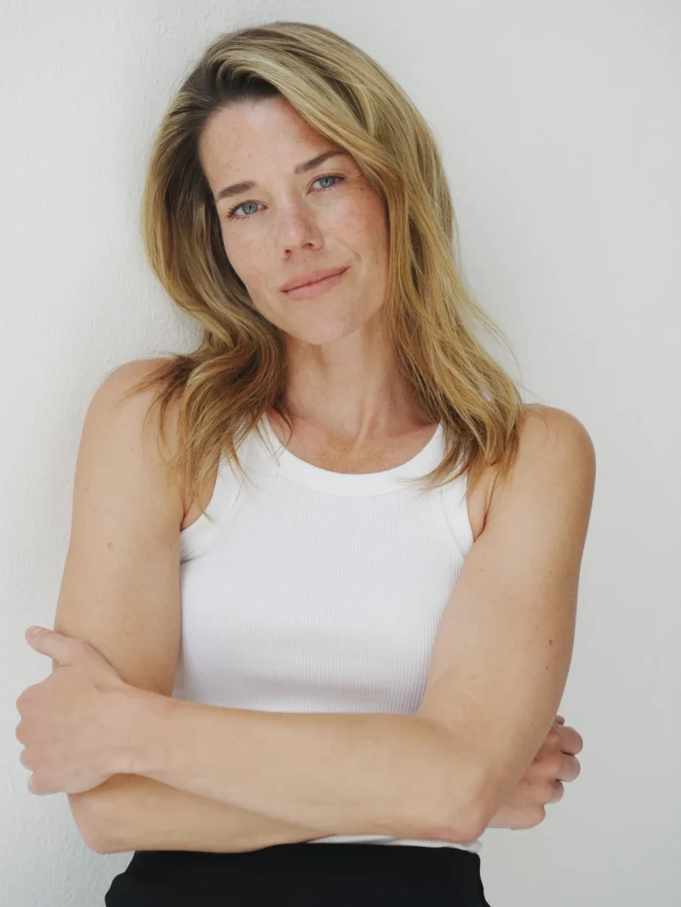 Woman in white tank top against wall