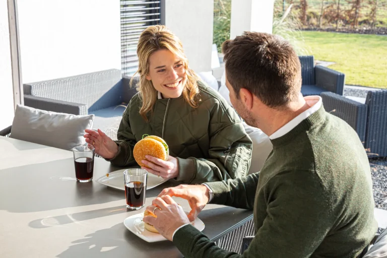 Couple enjoying burgers and drinks on sunny patio