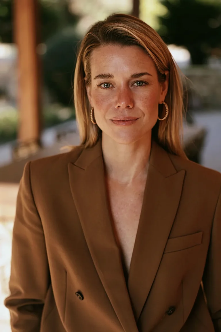 Woman in brown blazer with gold hoop earrings