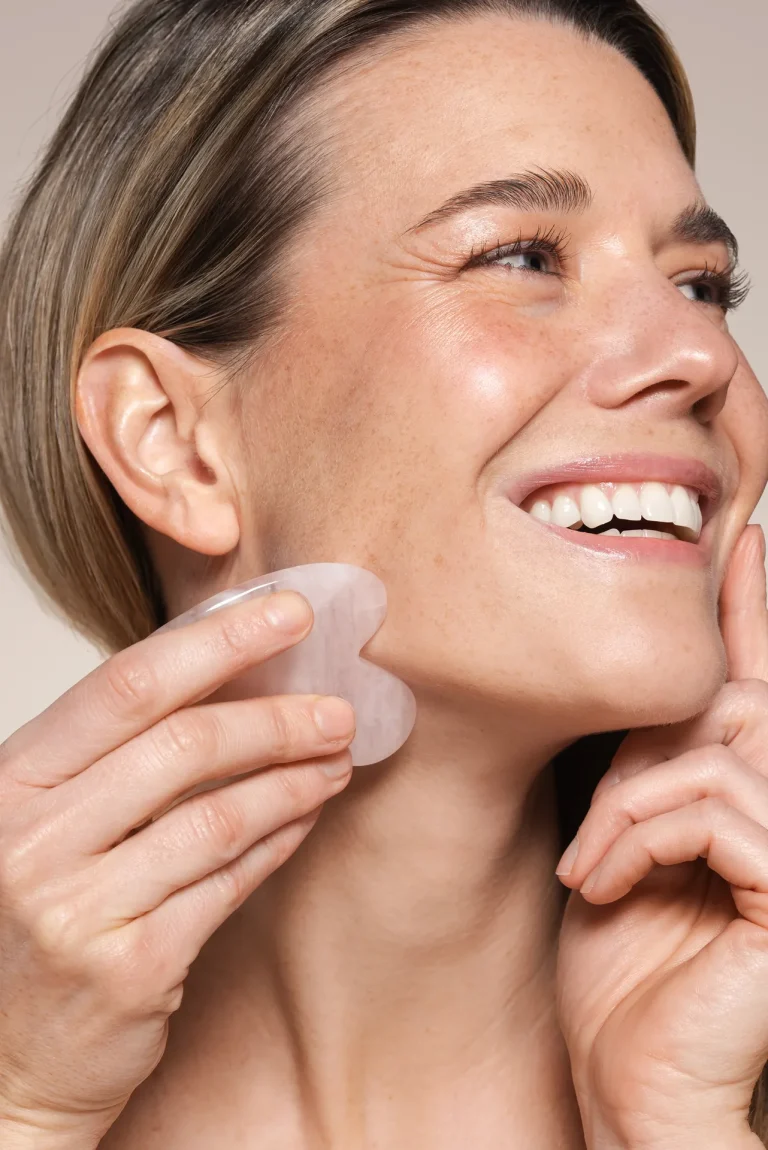 Woman using gua sha tool on jawline