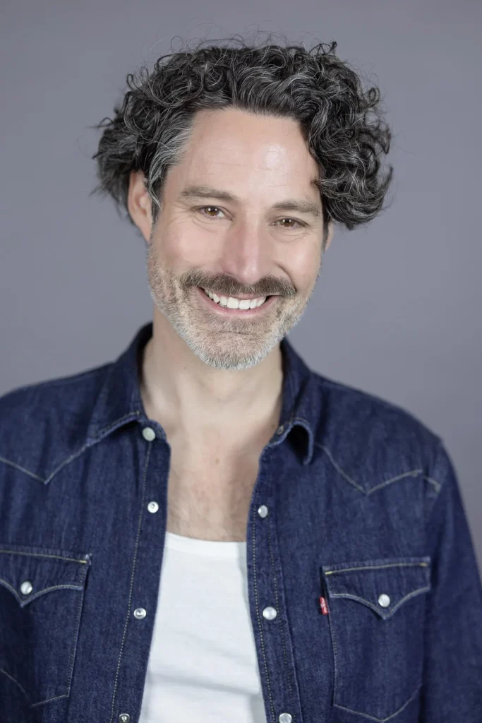 Lächelnder Mann mit lockigem Haar und Bart