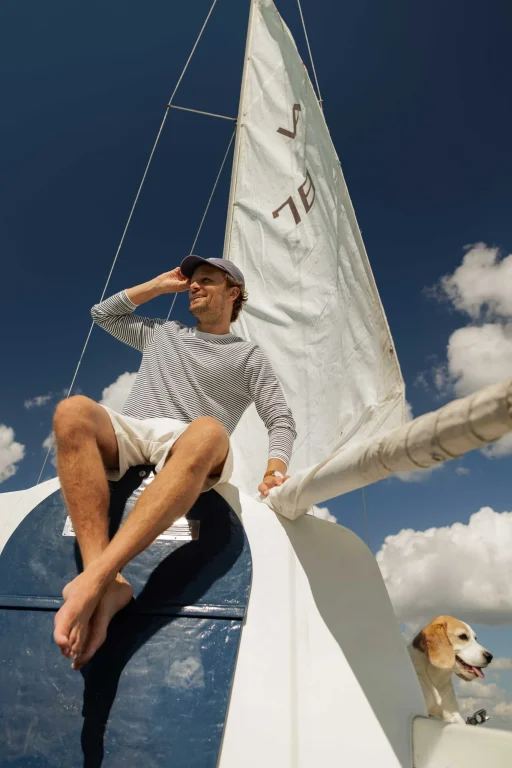 Mann und Hund auf Segelboot unter blauem Himmel