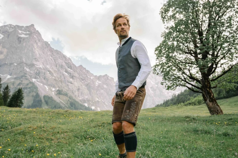 Mann in Tracht auf Alm vor Bergpanorama