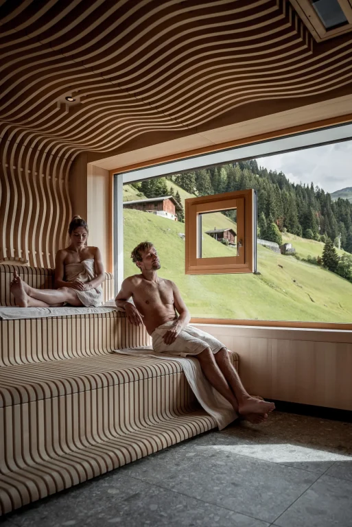 Zwei Menschen entspannen in Holzsauna mit Bergblick