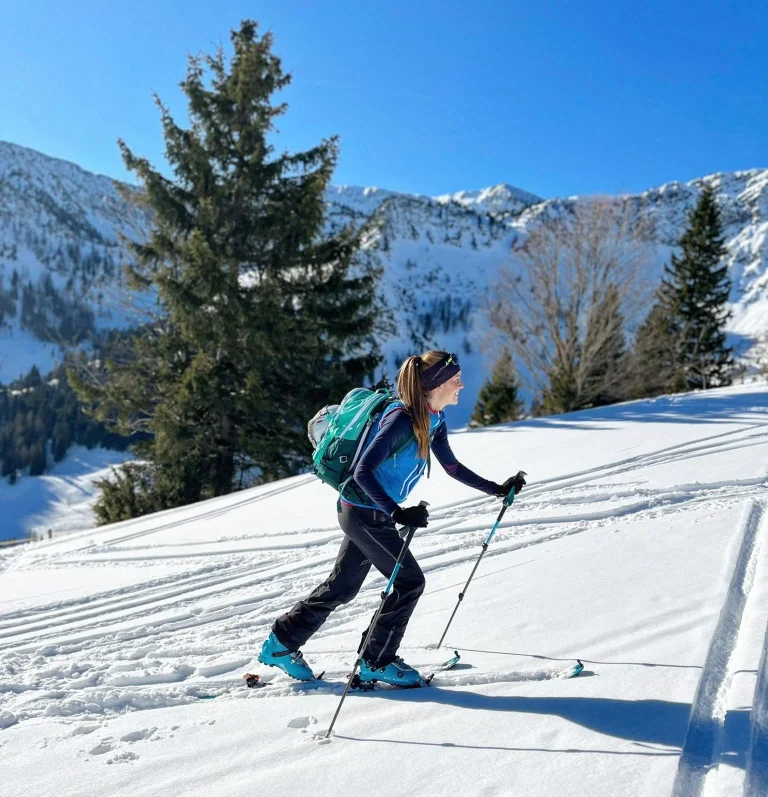 Frau beim Skitourengehen in verschneiten Alpen