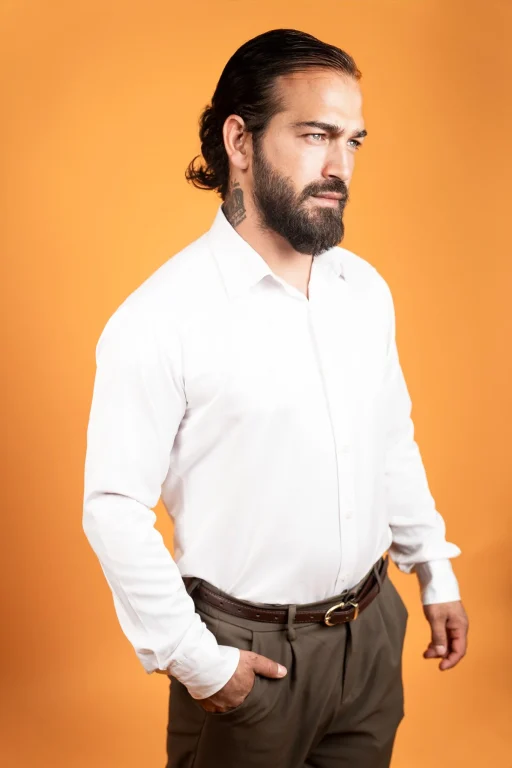Bärtiger Mann im weißen Hemd vor orangefarbenem Hintergrund