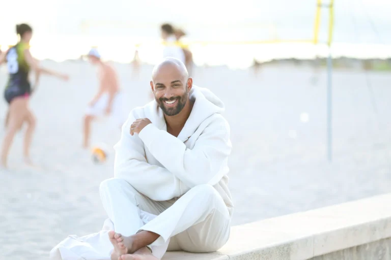 Lächelnder Mann im weißen Outfit am Strand