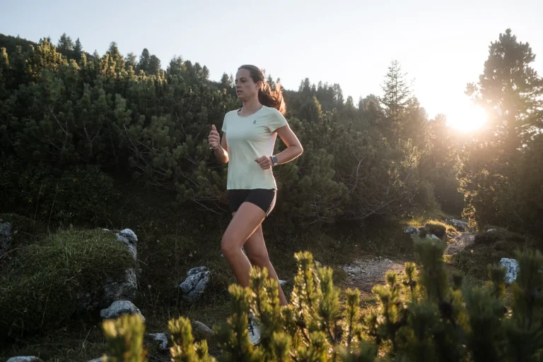Frau joggt bei Sonnenuntergang auf Waldpfad