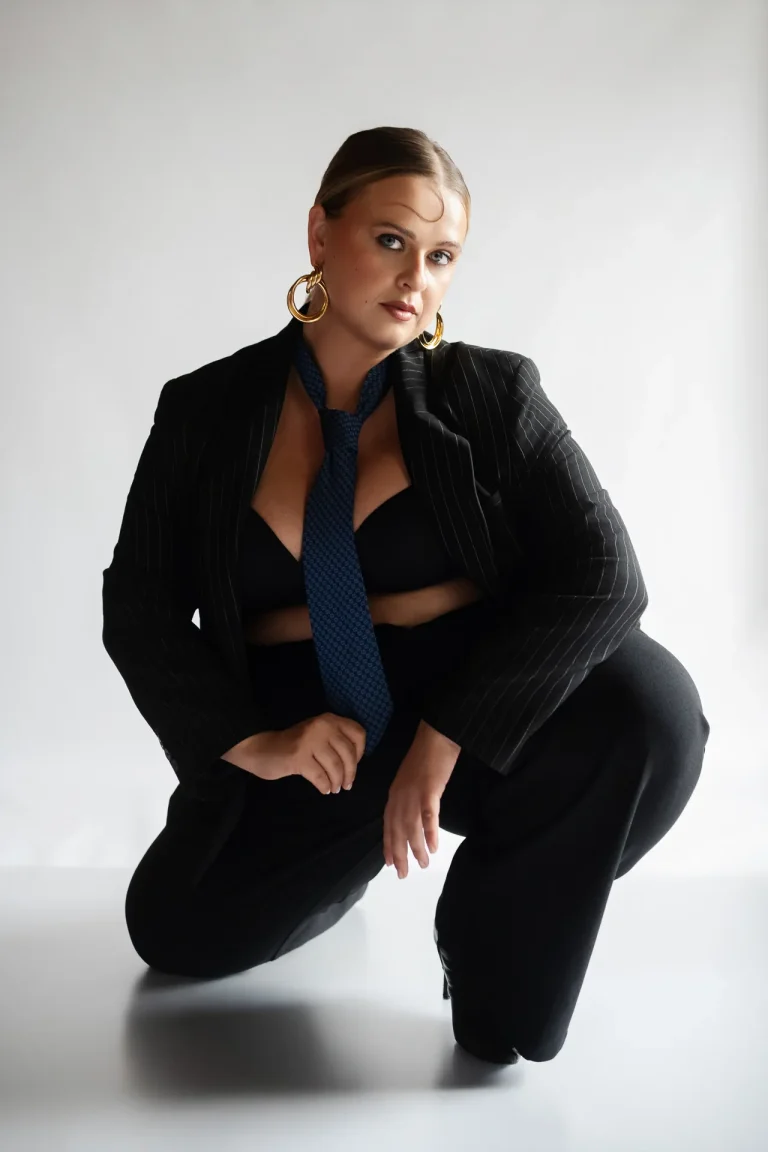 Woman in blazer and tie posing in studio