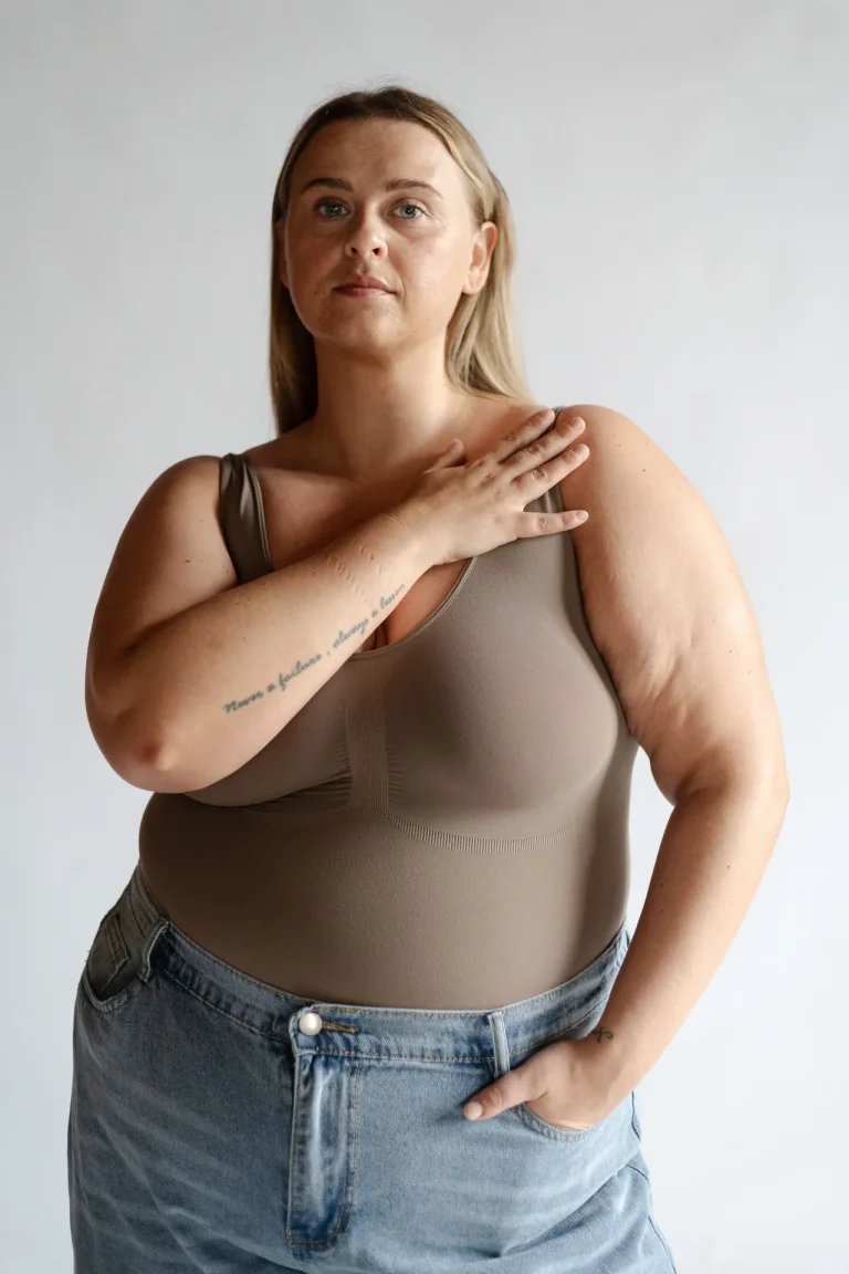 Woman in beige tank top and jeans posing