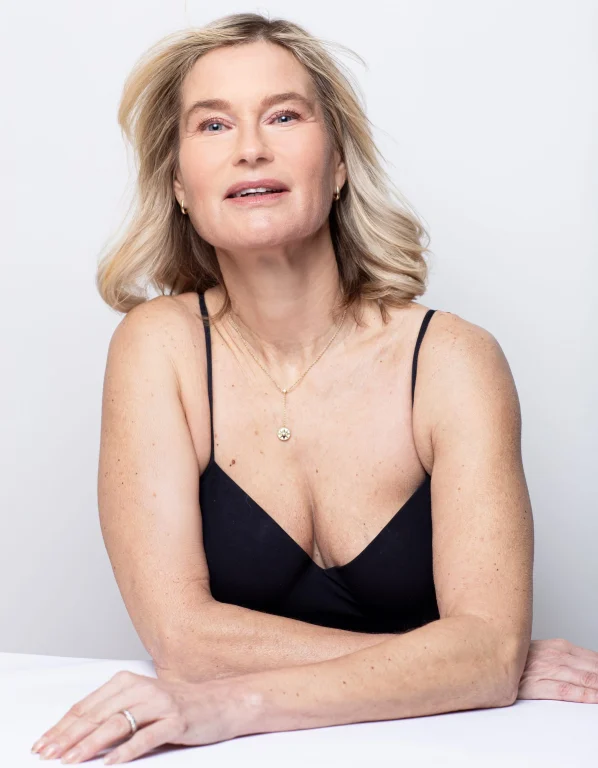 Blonde Frau im schwarzen Top vor hellem Hintergrund