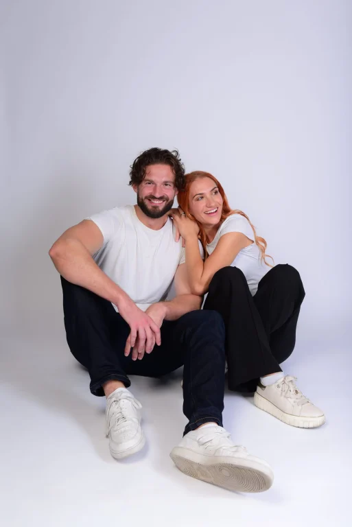 Lächelndes Paar sitzt eng beieinander im Fotostudio
