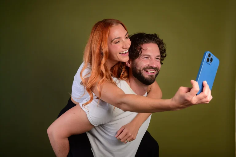 Lachendes Paar macht Selfie, Frau sitzt auf Schultern