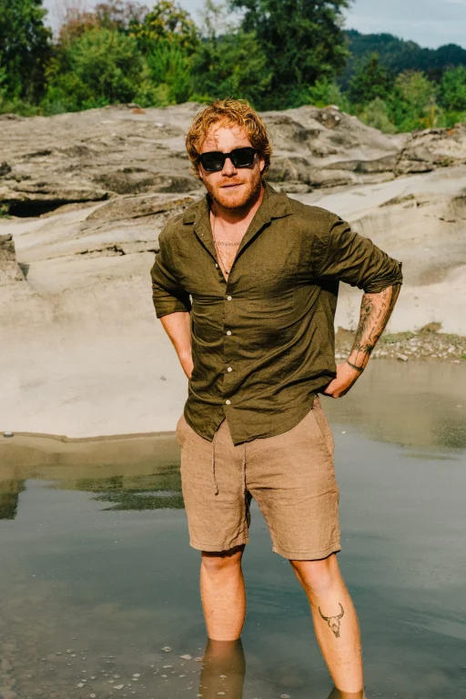 Mann mit Sonnenbrille steht in flachem Wasser