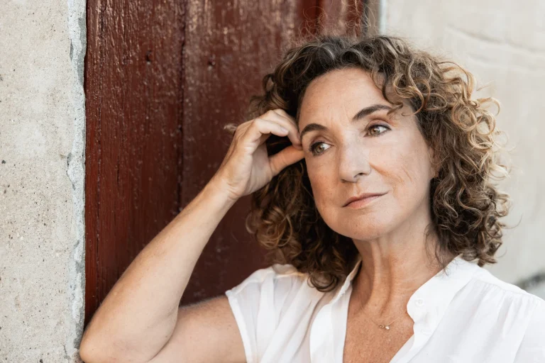 Nachdenkliche Frau mit Locken an einer Holztür