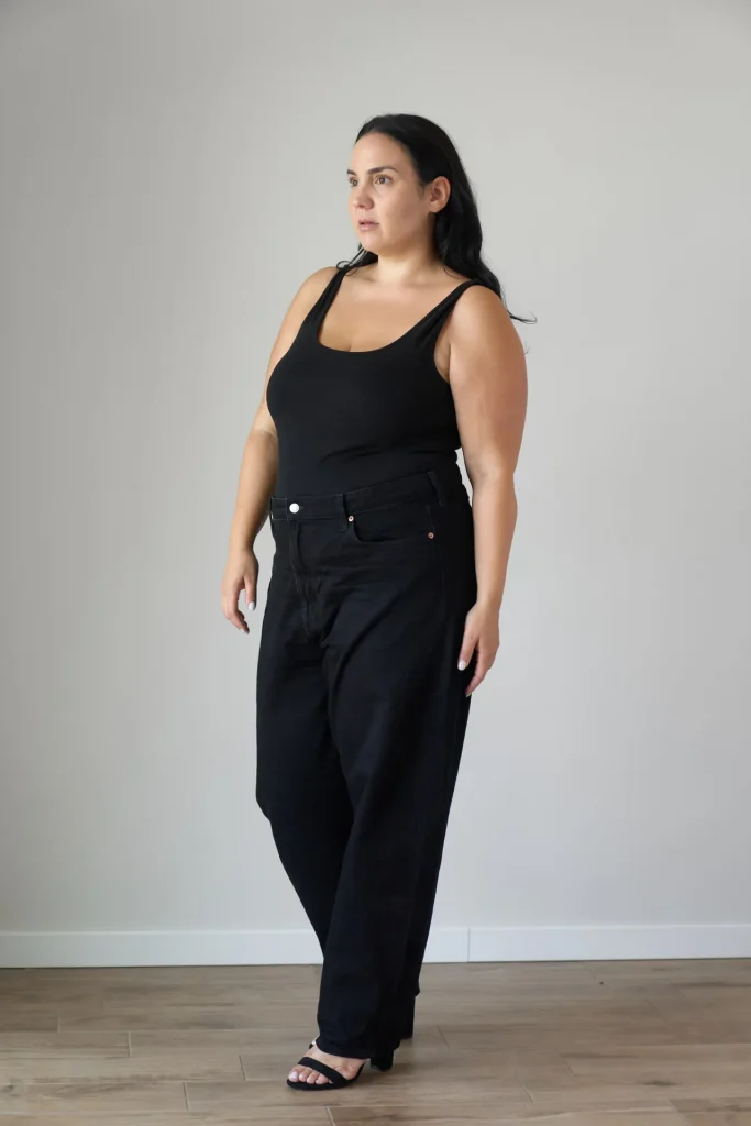 Frau in schwarzem Outfit vor heller Wand