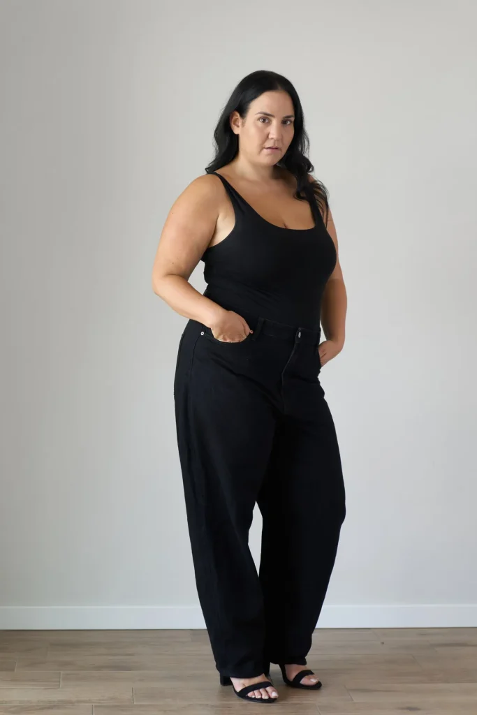 Frau in schwarzem Outfit vor grauer Wand