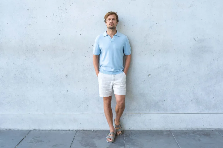 Mann in hellblauem Poloshirt vor Betonwand