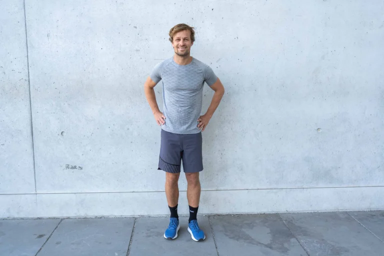 Lächelnder Mann in Sportkleidung vor Betonwand