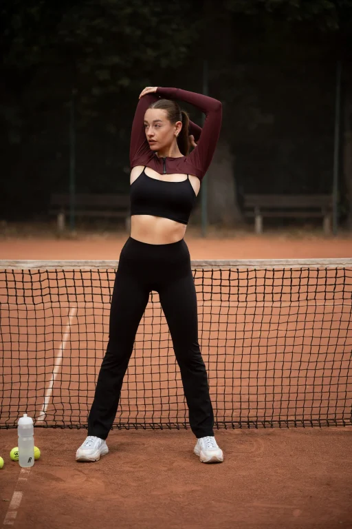 Frau dehnt sich auf einem Tennisplatz am Netz
