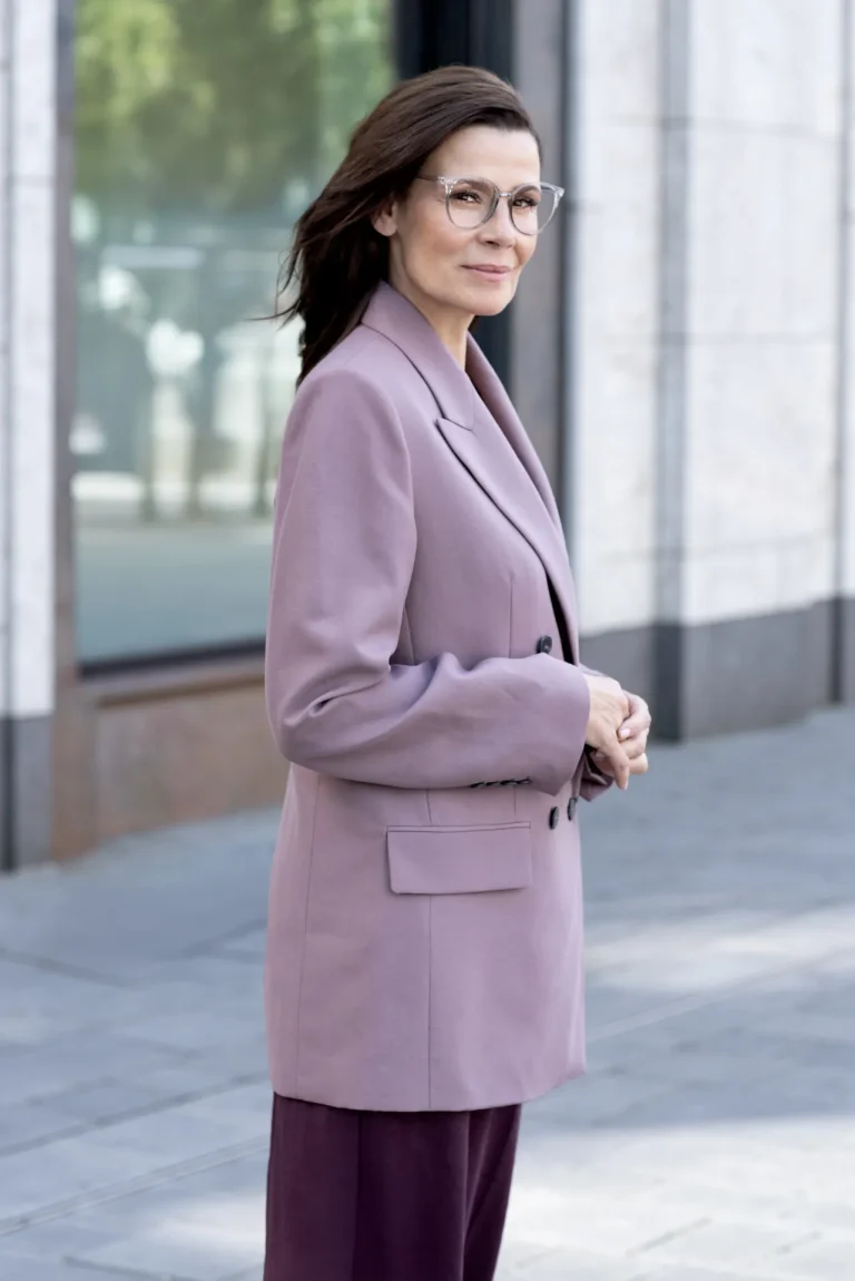 Elegant gekleidete Frau mit Brille vor Gebäude