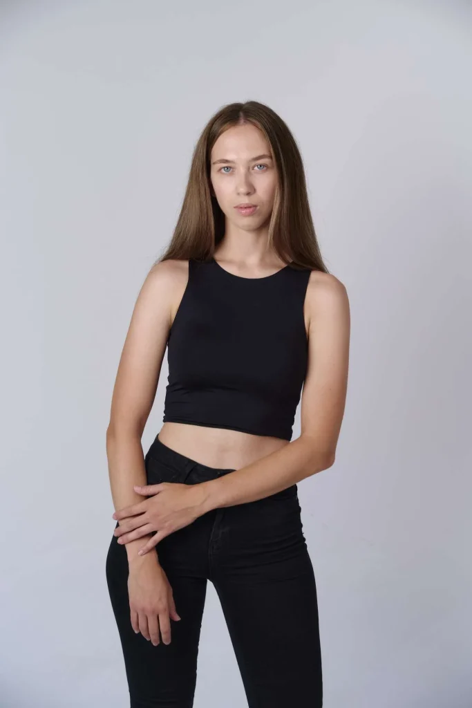 Junge Frau in schwarzem Crop-Top vor grauem Hintergrund