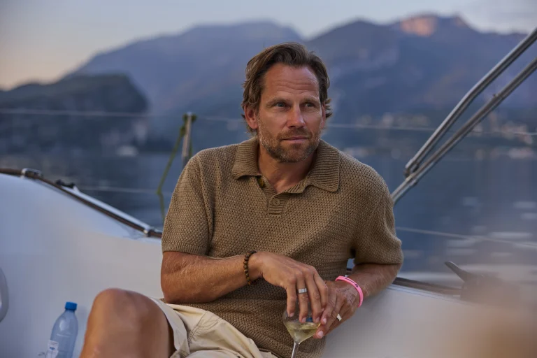 Mann auf Yacht mit Weinglas bei Sonnenuntergang