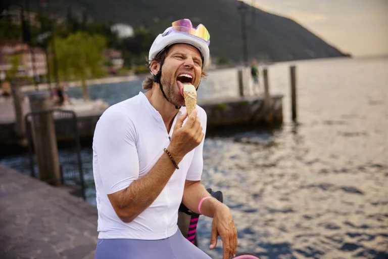 Radfahrer mit Helm isst Eis am See