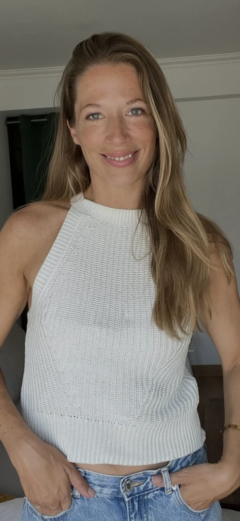 Lächelnde Frau im weißen Stricktop und Jeans