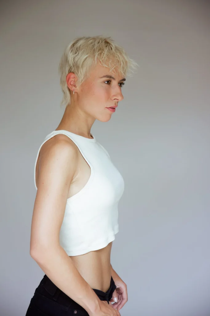 Frau mit blondem Pixie-Cut im weißen Crop-Top