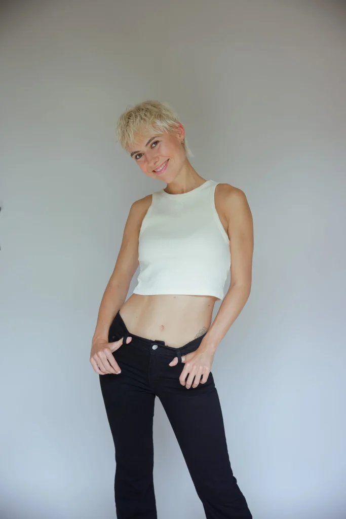 Lächelnde Frau mit kurzem Blondhaar in weißem Top