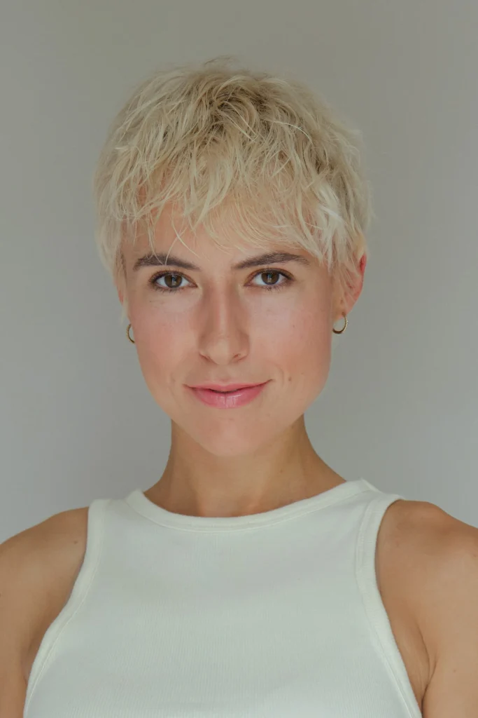 Frau mit kurzem blondem Pixie-Schnitt und goldenen Creolen
