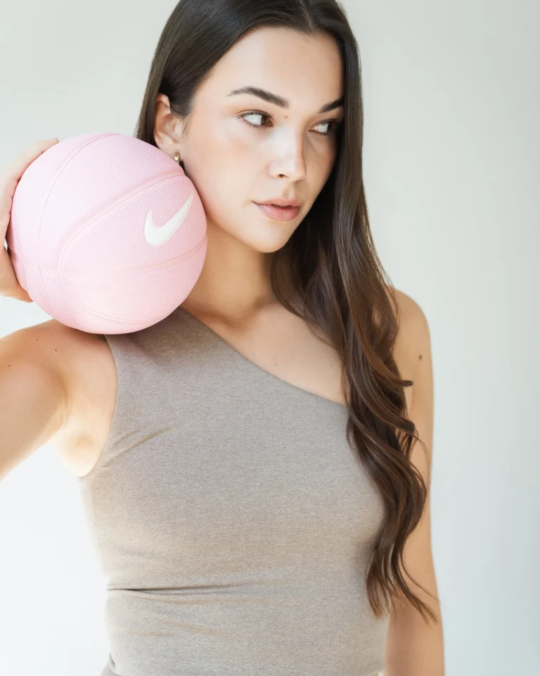 Frau mit rosa Basketball auf der Schulter