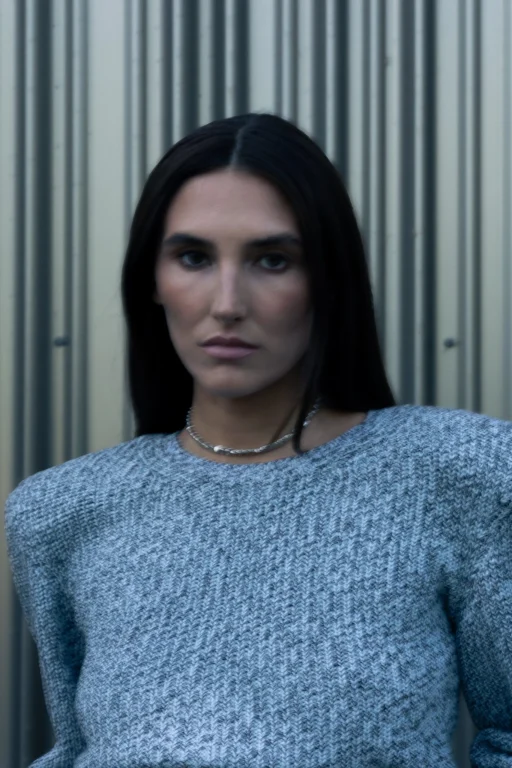 Porträt einer Frau im grauen Strickpullover vor Metallwand