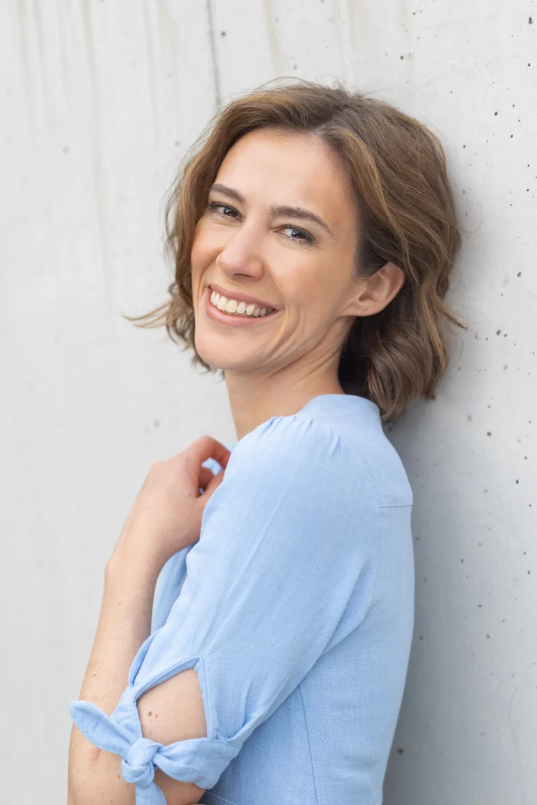 Lächelnde Frau in blauer Bluse an Betonwand