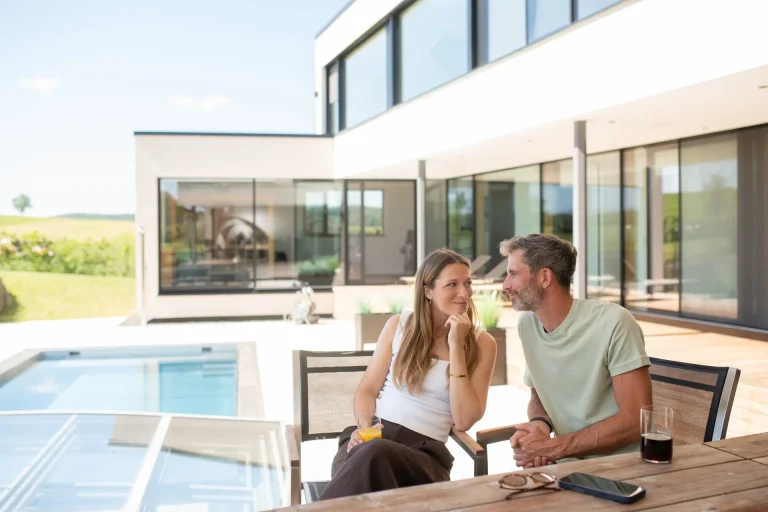 Paar auf Terrasse mit Pool vor modernem Haus