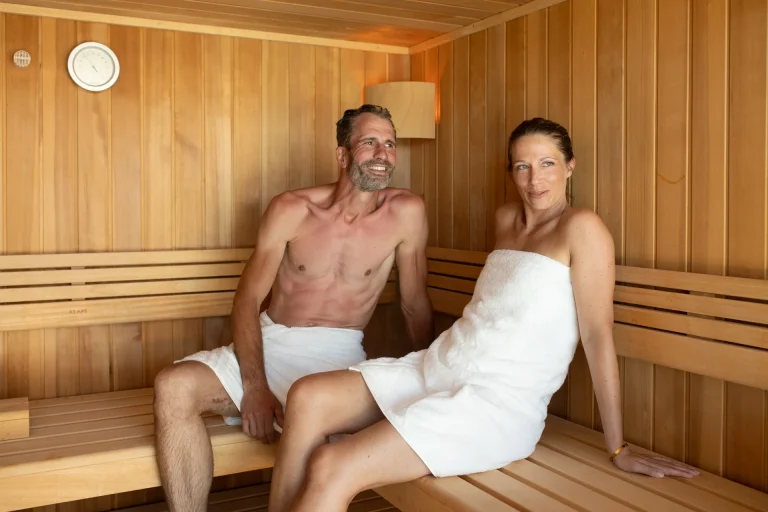 Paar entspannt in einer Holzsauna mit Handtüchern