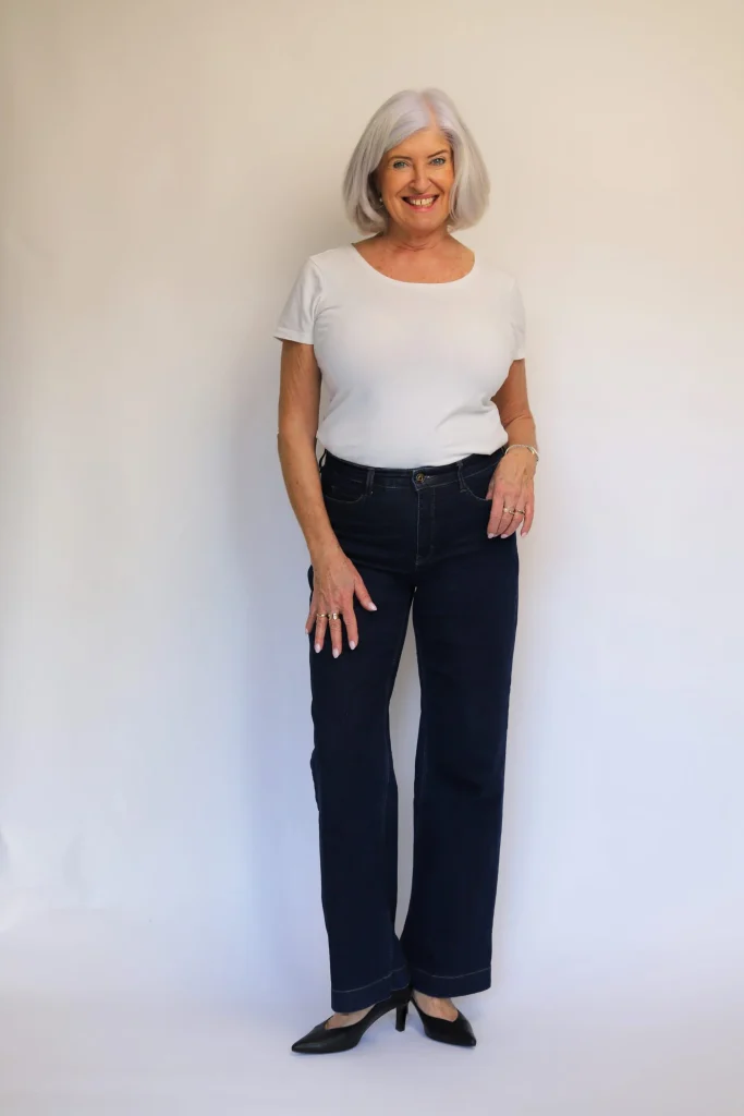 Lächelnde Frau in weißem Shirt und dunkler Jeans