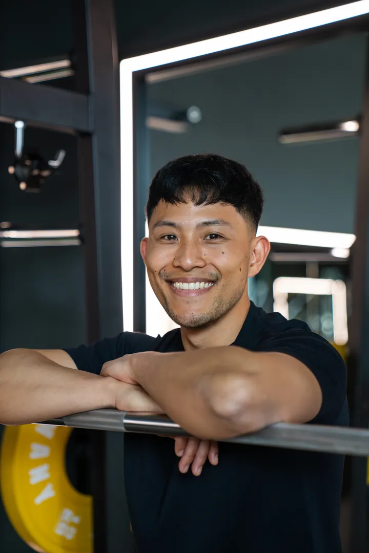 Lächelnder Mann im Fitnessstudio lehnt an Geländer