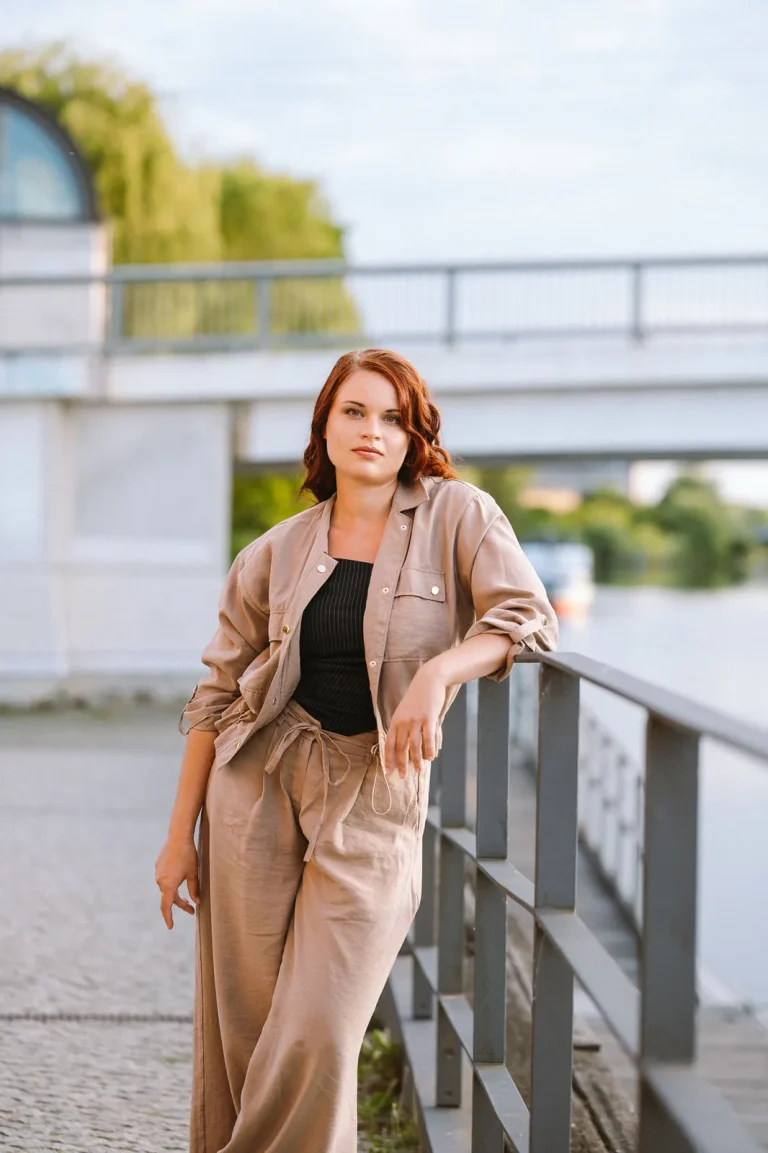 Woman leaning on railing by riverside walkway