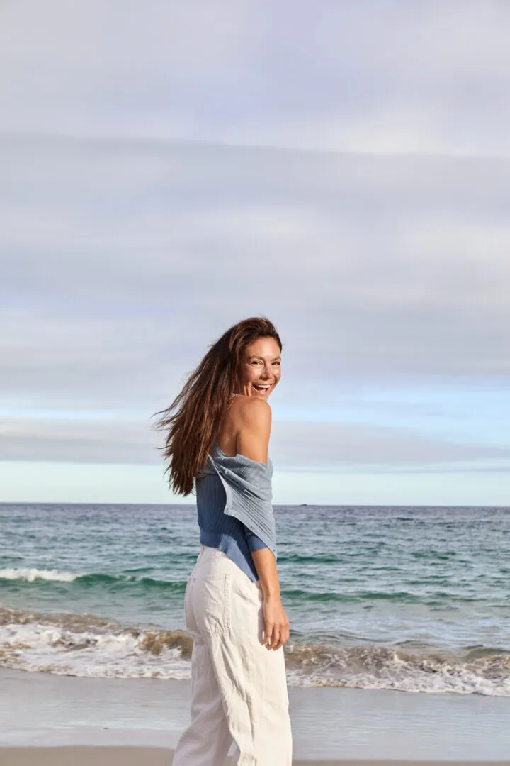 Mara Models - Lächelnde Frau am Strand vor dem Meer