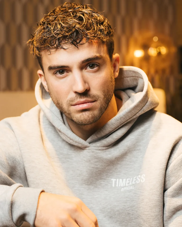 Young man in gray hoodie, warm indoor portrait