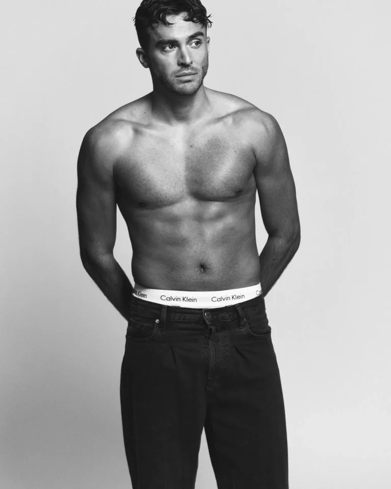 Shirtless man in jeans against plain background