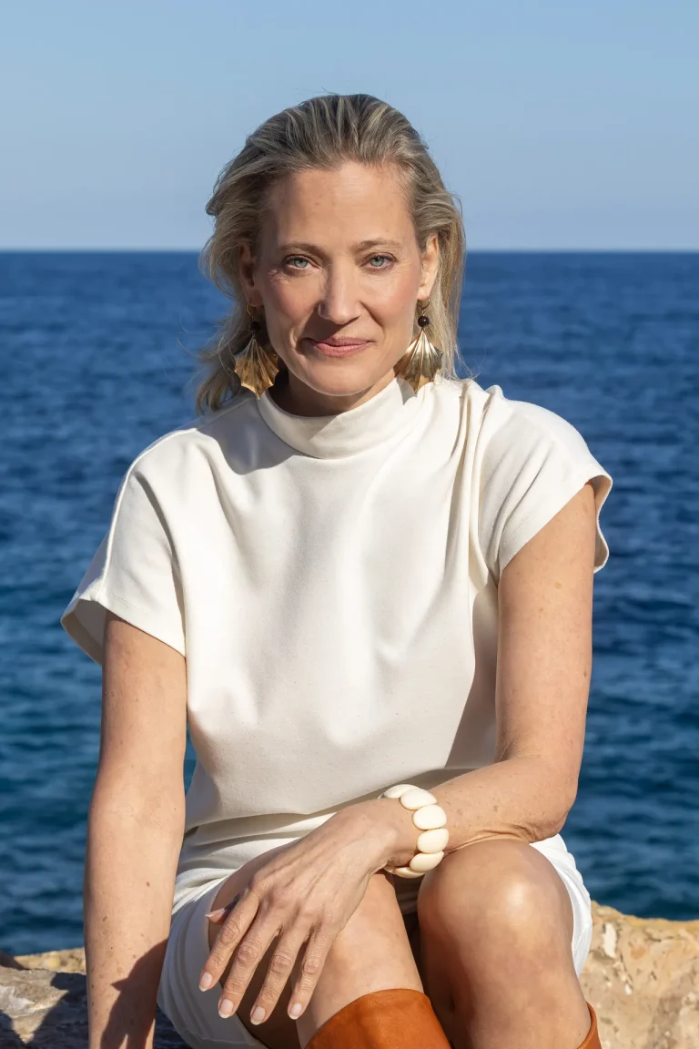Frau sitzt am Meer mit weißem Kleid